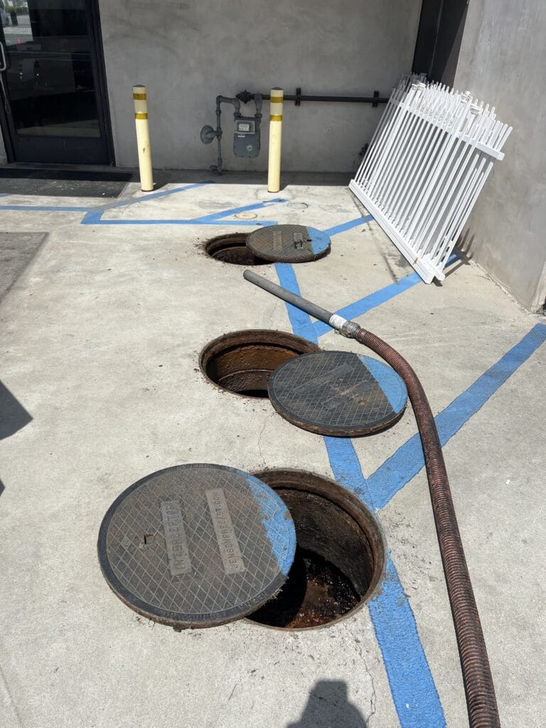 open grease interceptor with technicians performing grease interceptor cleaning service in Los Angeles restaurant