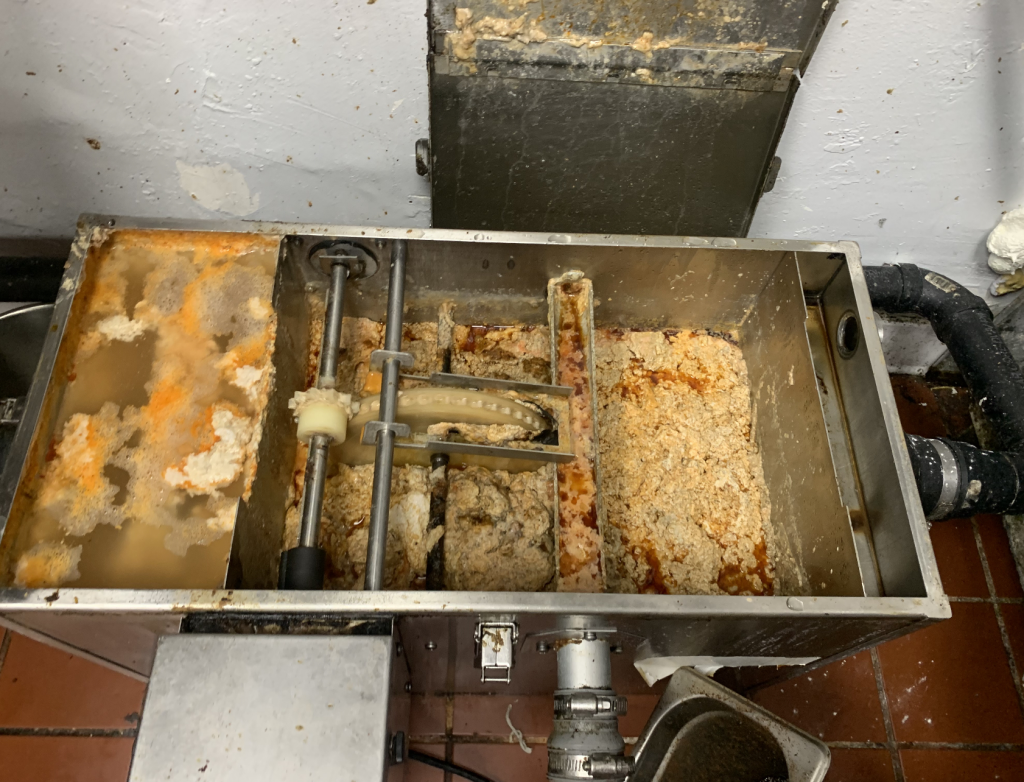 full grease trap with heavy grease buildup before grease trap cleaning Los Angeles commercial kitchen