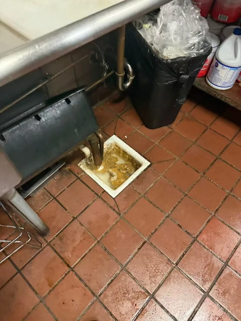 grease trap cleaning operation inside Los Angeles restaurant kitchen removing grease buildup safely
