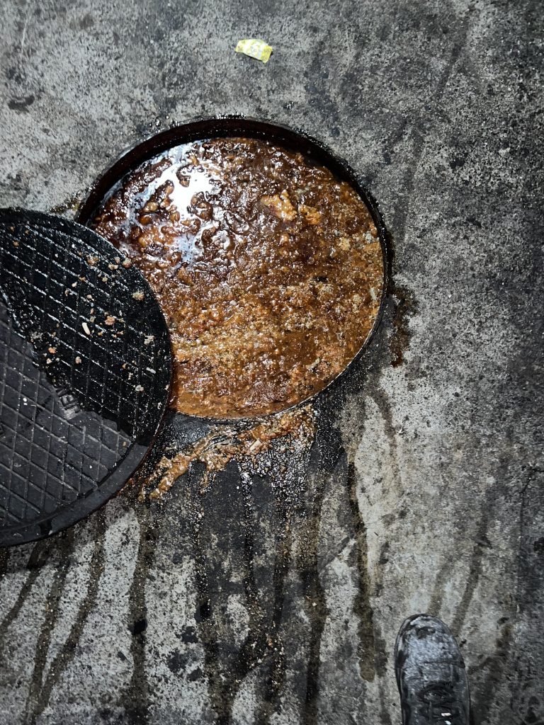 technician performing grease trap repair inside restaurant kitchen in Los Angeles