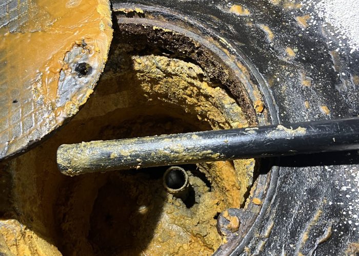 Grease Trap Requiring Professional Odor Elimination and Grease Trap Deodorizing Dirty grease trap emitting foul odors, in need of professional grease interceptor odor control